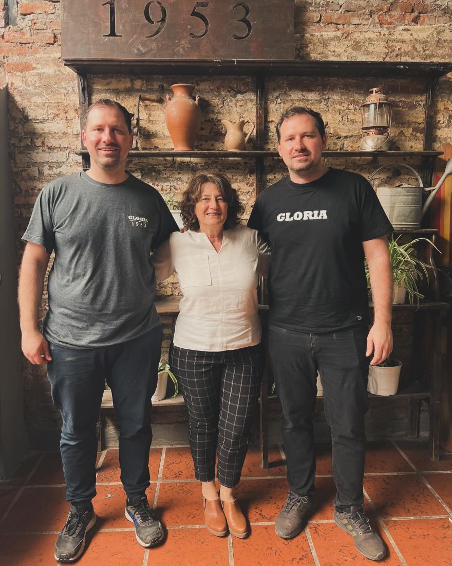 Tres integrantes de la familia de Gloria en el salón, frente a la pared de ladrillo