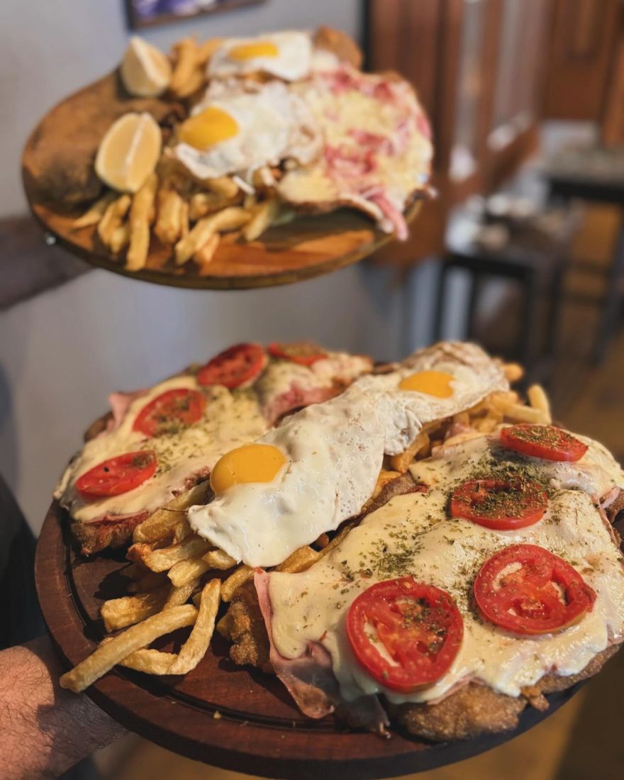Dos tablas de milanesas a caballo con huevo frito, tomate y papas fritas